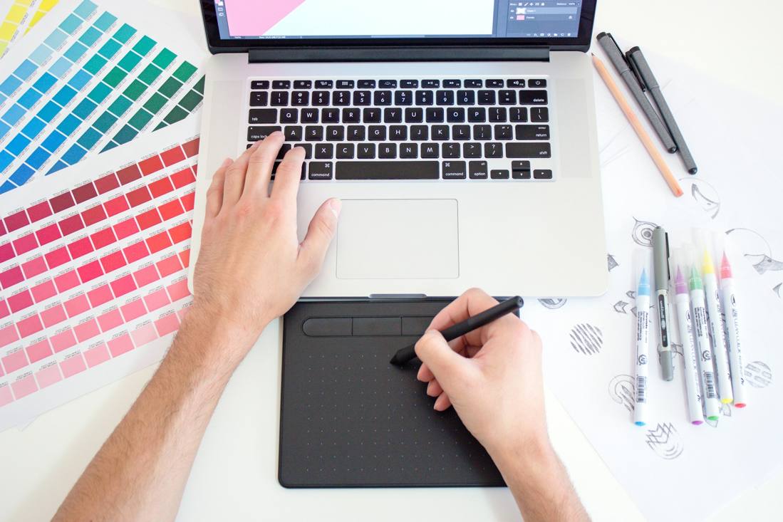 Portfolio Mediagramma - postazione di lavoro creativa con Mac, tavoletta grafica Wacom, mazzette Pantone e strumenti da disegno